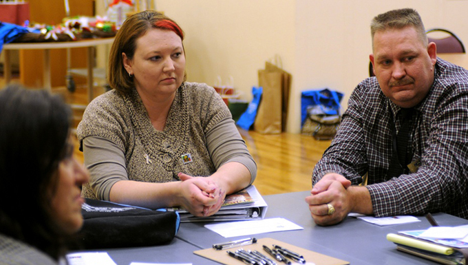 Adults sitting at a table filling out paperwork.