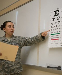 An airmen pointing at an eye chart.