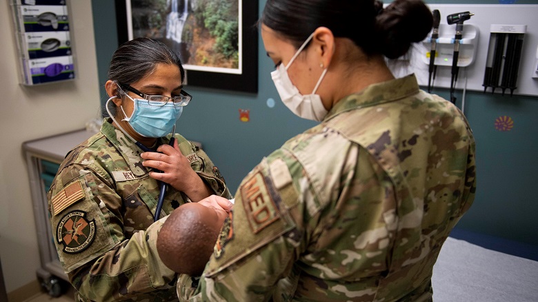 Image of two Airmen treating a child patient.