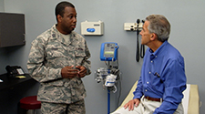  Image of an Airman talking to an older male patient at the doctor's office