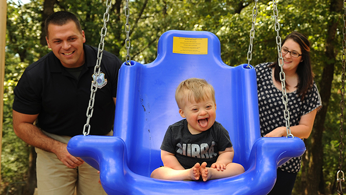 Image of a family pushing a child in a swing