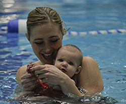 A mother in a swimming pool with her baby.